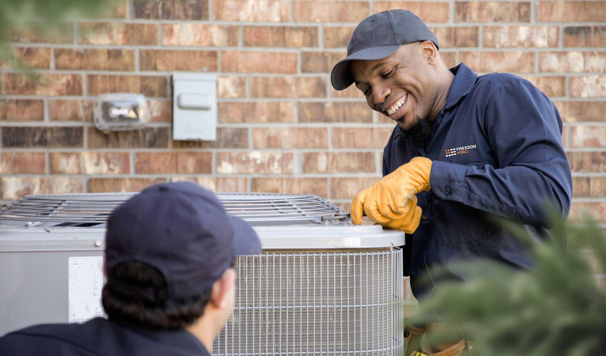 Man in navy uniform working on AC Unit